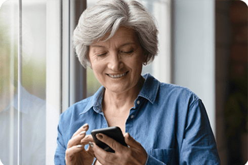Mujer mayor revisando su teléfono celular. Transformación digital - Banco Interamericano de Desarrollo - BID